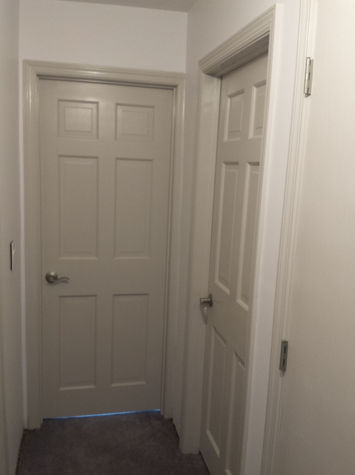 De hal. Met grijze deuren en nikkelkleurig deurbeslag